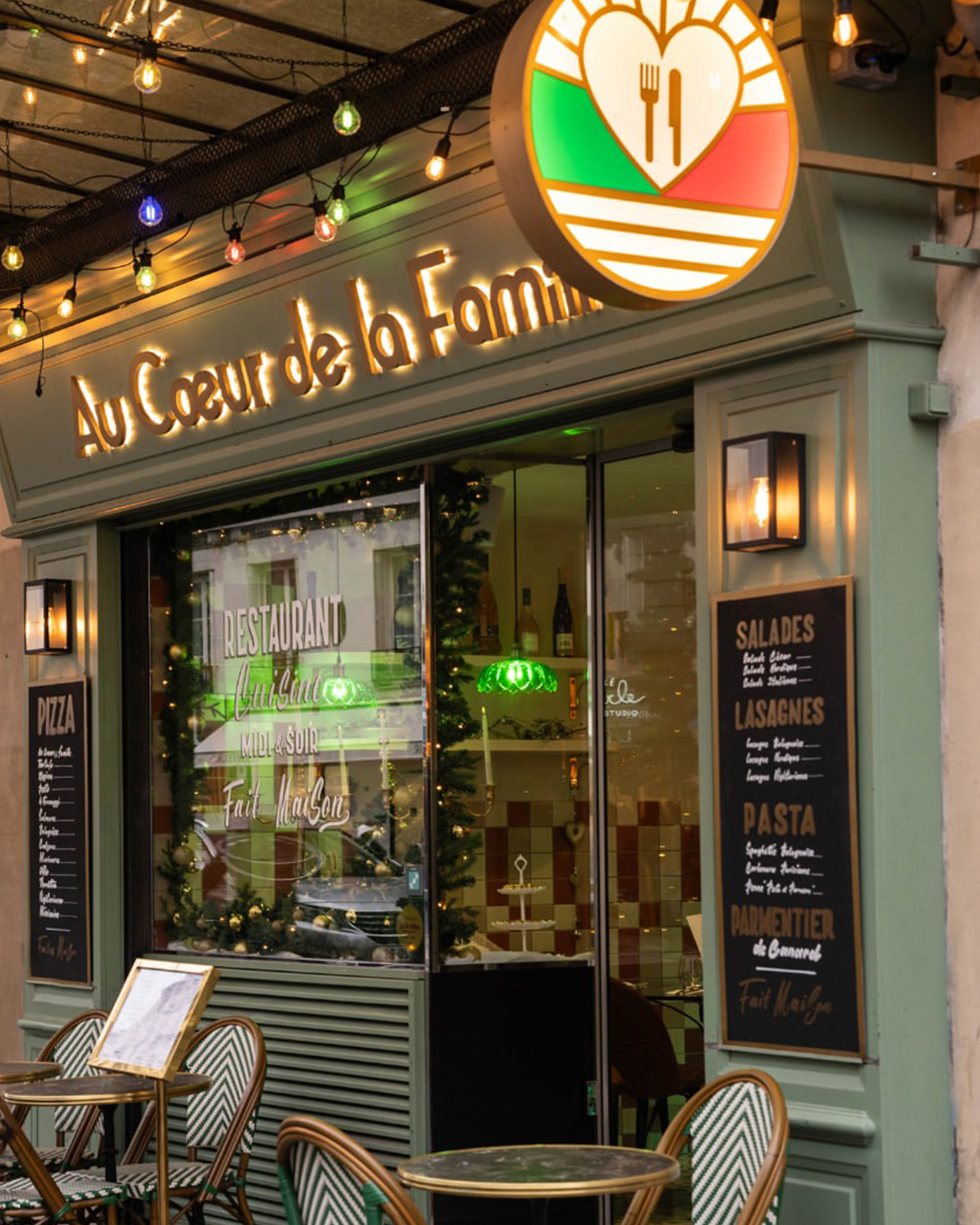 La façade et la terrasse du restaurant Au Cœur de la Famille, sous ses guirlandes lumineuses