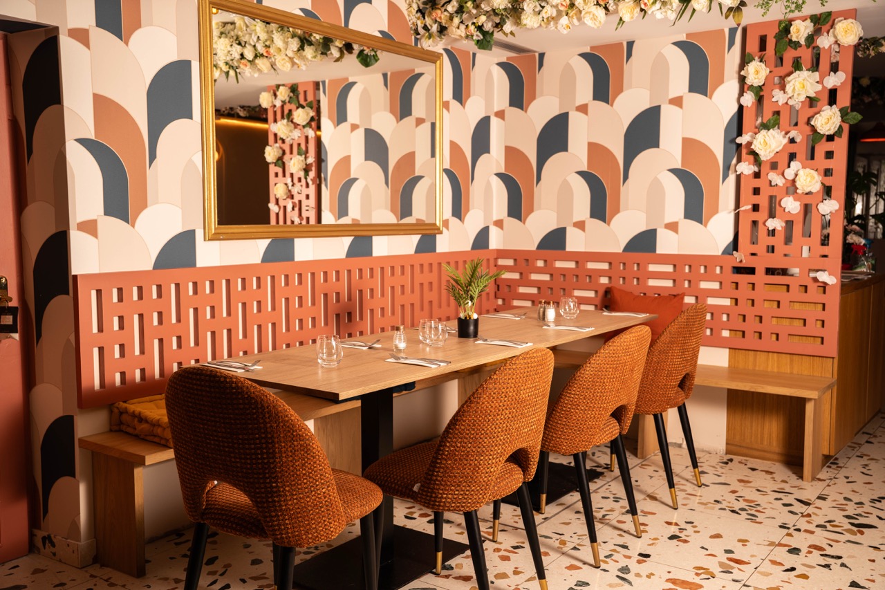 La salle du restaurant : banquettes terracotta, tables en bois et sol terrazzo